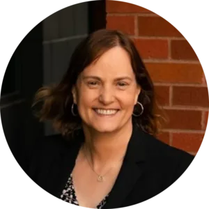 Headshot of Robyn Tanguay wearing a black coat in front of a red brick wall.